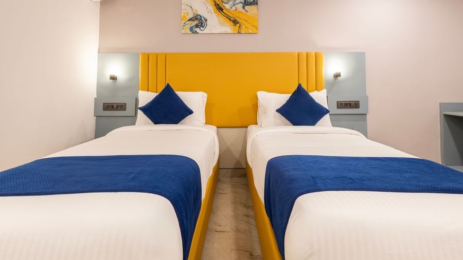 Close up of Superior Room featuring a bed with blue and white bedding, a yellow headboard, and modern furnishings including a desk and TV - Beestay Hotel Financial District, Hyderabad