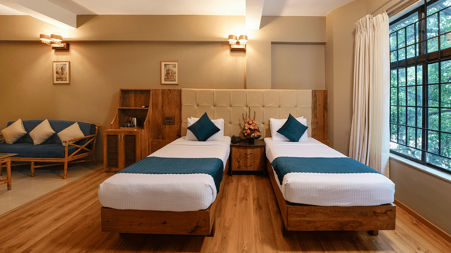 An image of a twin bed Deluxe Room with warm tones and modern amenities - Cross Roads Inn, Bengaluru