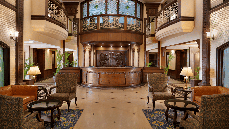 A multi-storey lobby area featuring a central reception desk, wooden pillars, and seating arrangements at Ramada by Wyndham Mussoorie Mall Road.