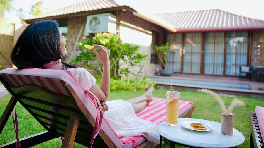 A woman seating on a lounge chair with drinks beside her at Surpura Bagh.