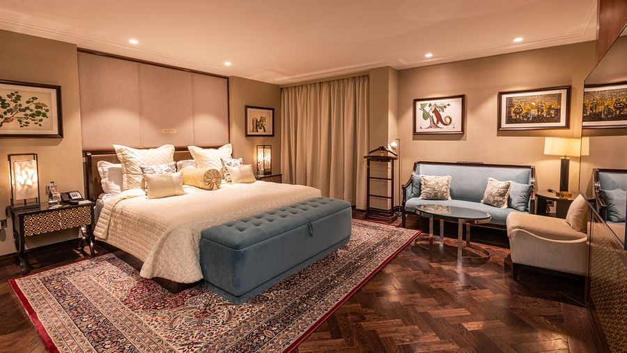 Luxury King Bed Room at The Claridges New Delhi, featuring a cosy king sized bed with plush pillows, bedside lamps, and a sofa seating area in the corner
