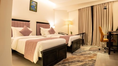 A room with twin beds and a desk with chair at Pride Elite Daman.