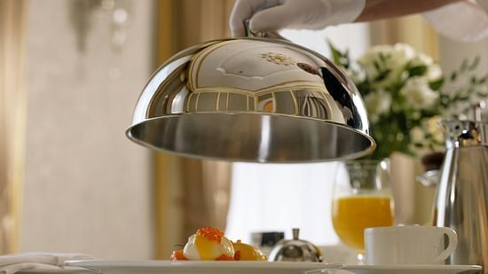 a person lifting a cloche in a hotel room