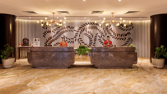 Two receptionists at the lobby of Pride Premier Nagpur desk doing namaste which is a way to greet guests.