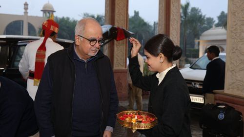 An image of a hotel attendee welcoming a senior citizen with petals and small earthen lamp - Heritage Village Resorts & Spa