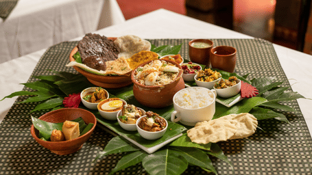 image of a full platter of food served on plantain leaves at Hoysala Village Resort, Hassan