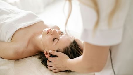 A therapist performing a soothing head massage on a client to promote relaxation.