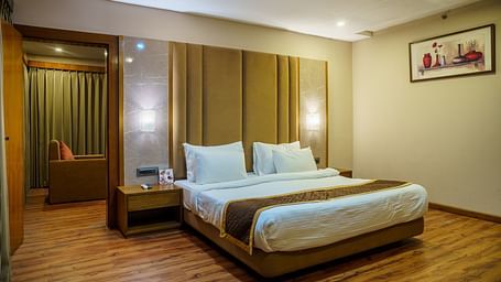 A room at Orsino Spa Resort with a bed featuring a light-coloured headboard, a bedside table, and wooden accents.