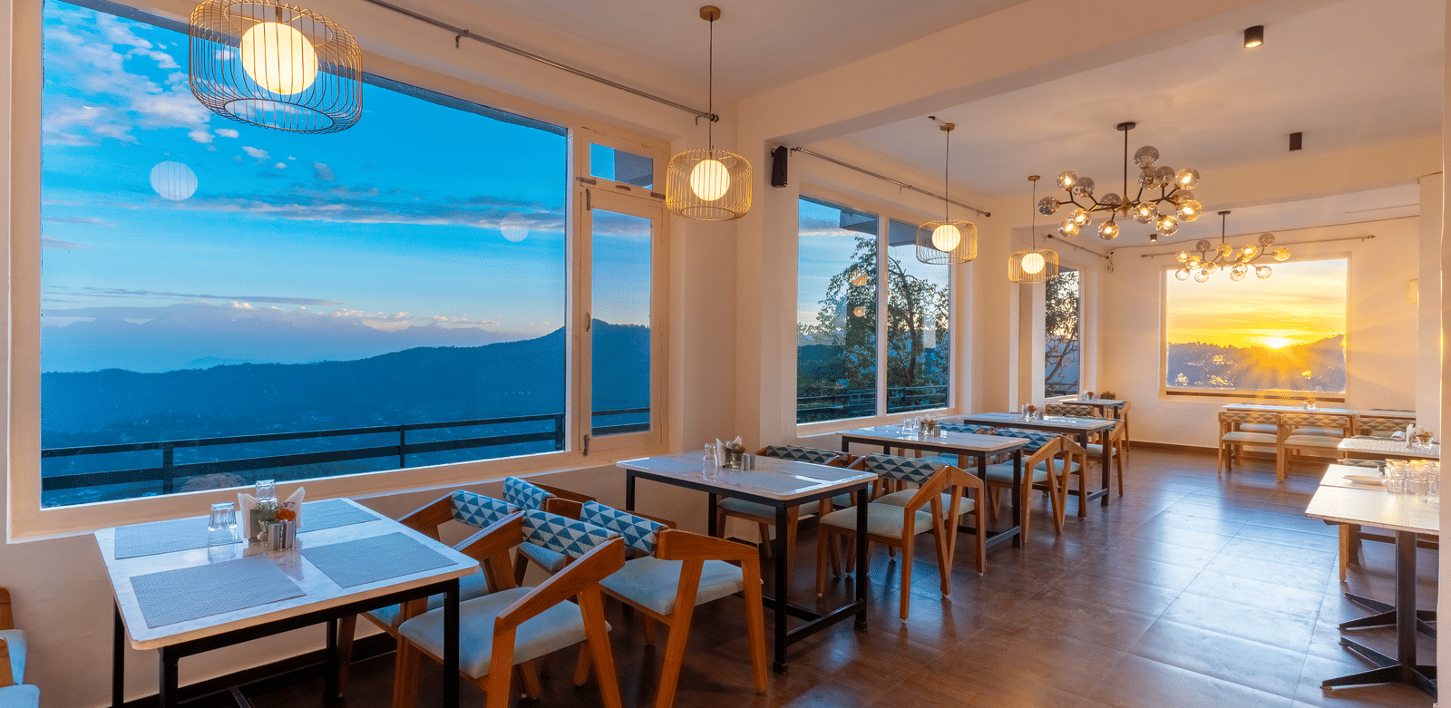 An indoor restaurant area with glowing spherical lights and large windows showing the evening sky at Himalayas Resort By The Lake Hill, Mukteshwar.