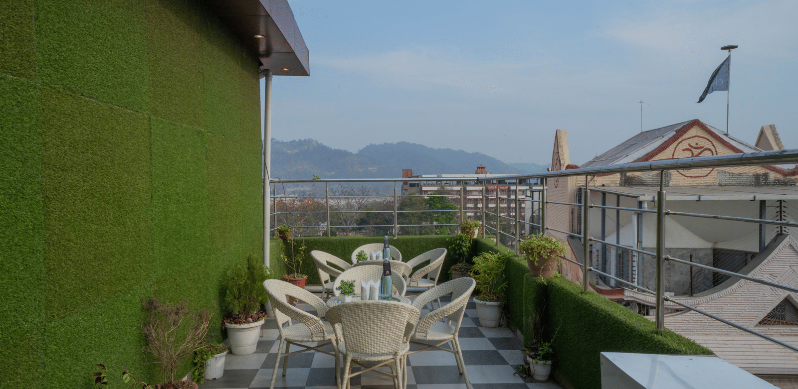Rooftop terrace seating area with tables and chairs and a view of the surrounding hills - Perfectstayz Premium at Har Ki Pauri Road (Ganga Heights)