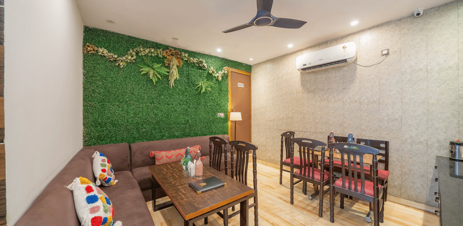 Lounge or dining area inside with a ceiling fan, tables, and chairs, featuring a green wall accent - Perfectstayz Premium at Har Ki Pauri Road (Ganga Heights)