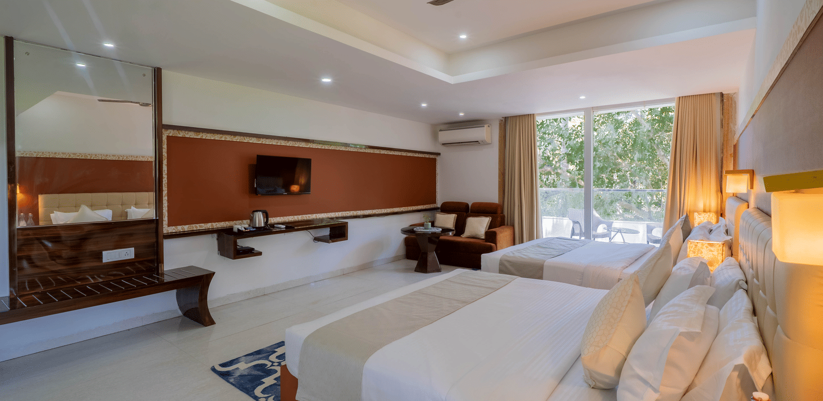 A large, bright hotel bedroom featuring 2 double beds, stylish modern wooden furniture, and ceiling fans - Perfectstayz Premium Goa Continental