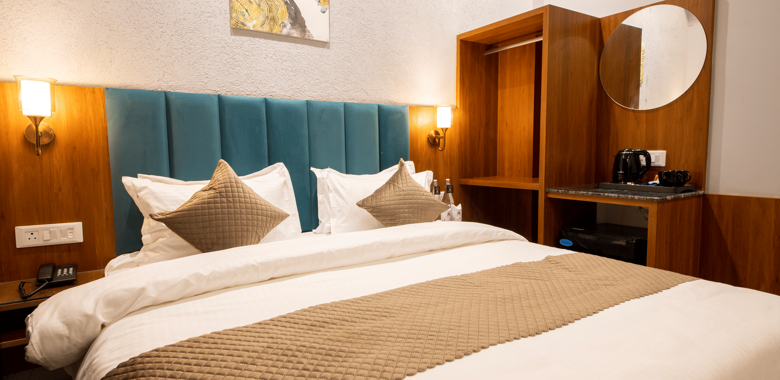 A bedroom with a king size bed, wooden wardrobe, and wall lamps at Perfectstayz Premium Laxmi Heritage.