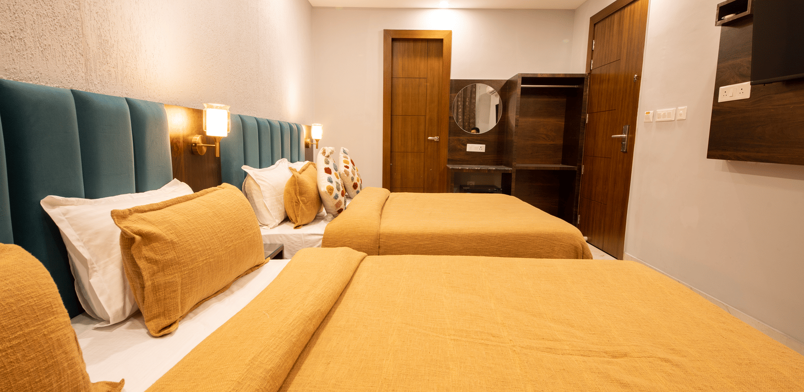 A bedroom with 2 king size beds, wooden vanity, and lighting at Perfectstayz Premium Laxmi Heritage.