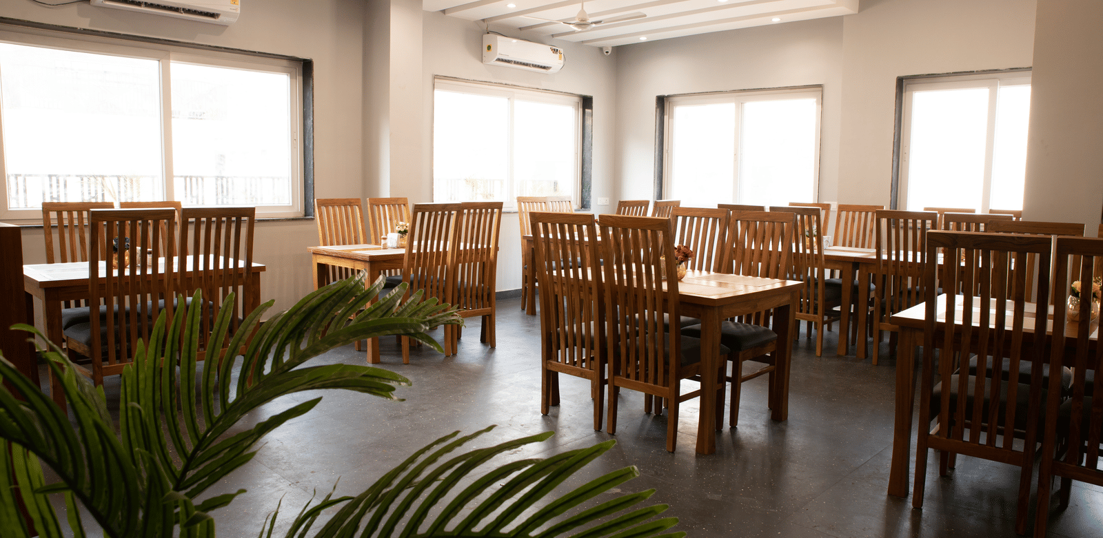 A dining area with tables, chairs, and a potted plant at Perfectstayz Premium Laxmi Heritage.