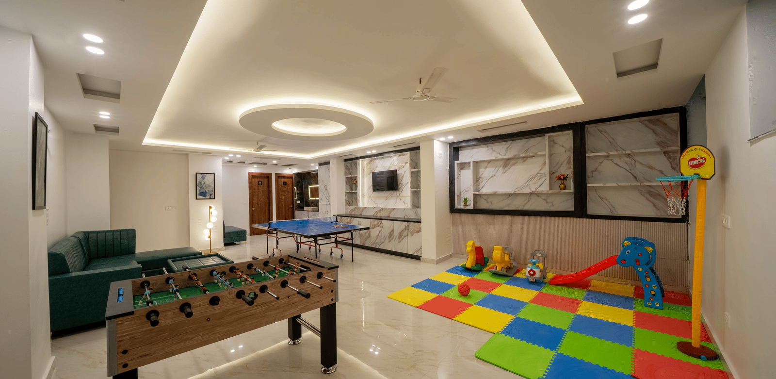 A room for recreation showing a foosball table, a play mat on the floor, and seating against the wall in Perfectstayz Premium Mystic Falls, Rishikesh.