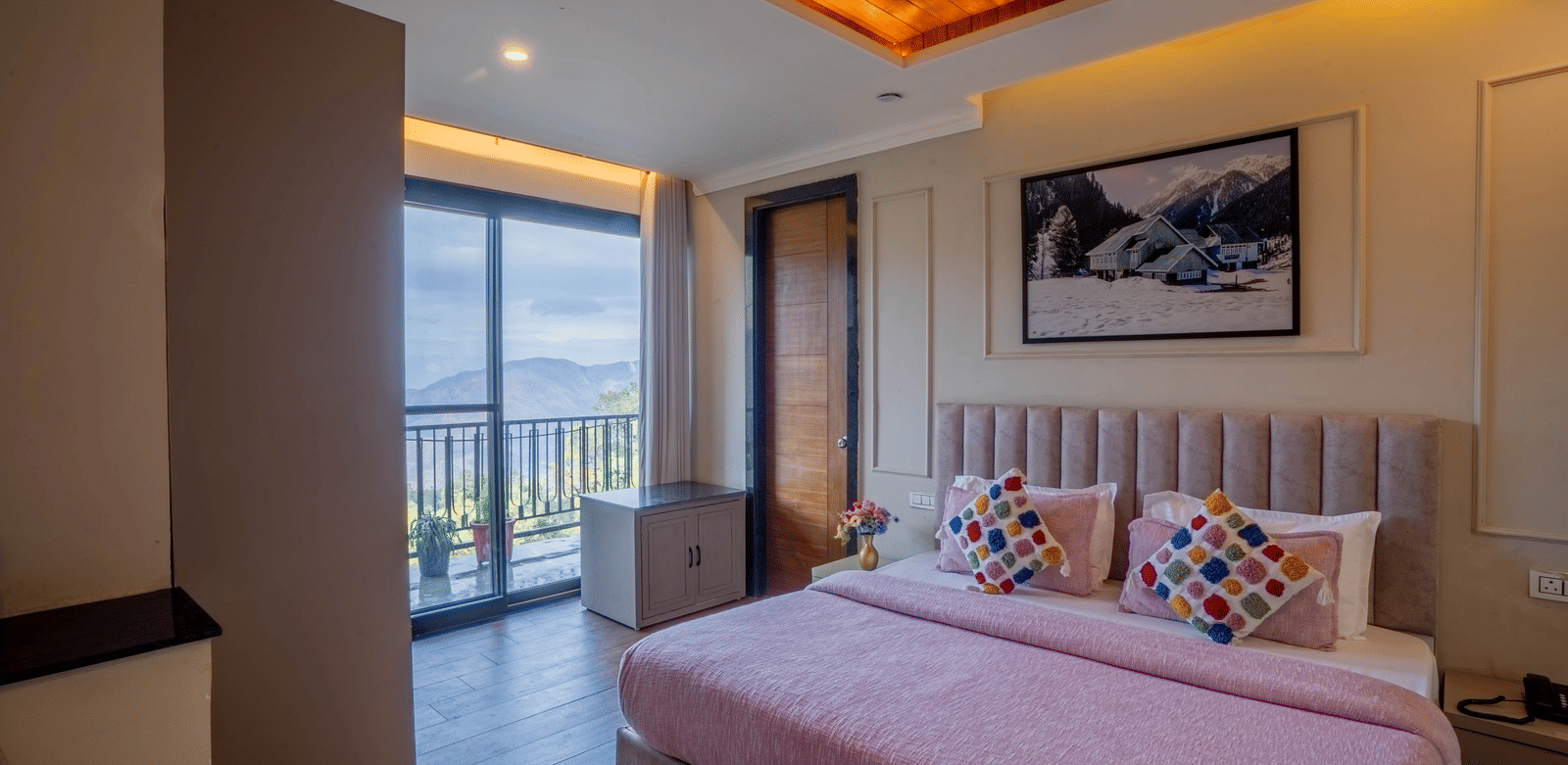 A wide-angle shot of the Family Suite With Shared Balcony & Valley View featuring a double bed with neatly-arranged cushions and a balcony in the side at Perfectstayz Premium Westend Mall Road, Mussoorie.