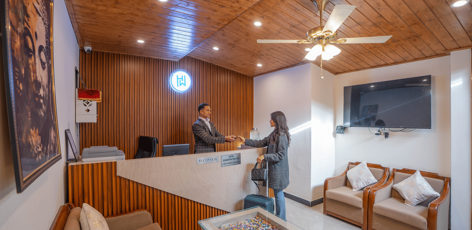 A wide-angle shot of the lobby area of the Perfectstayz Premium Westend Mall Road, Mussoorie, with a staff member giving the room key card to a female guest.