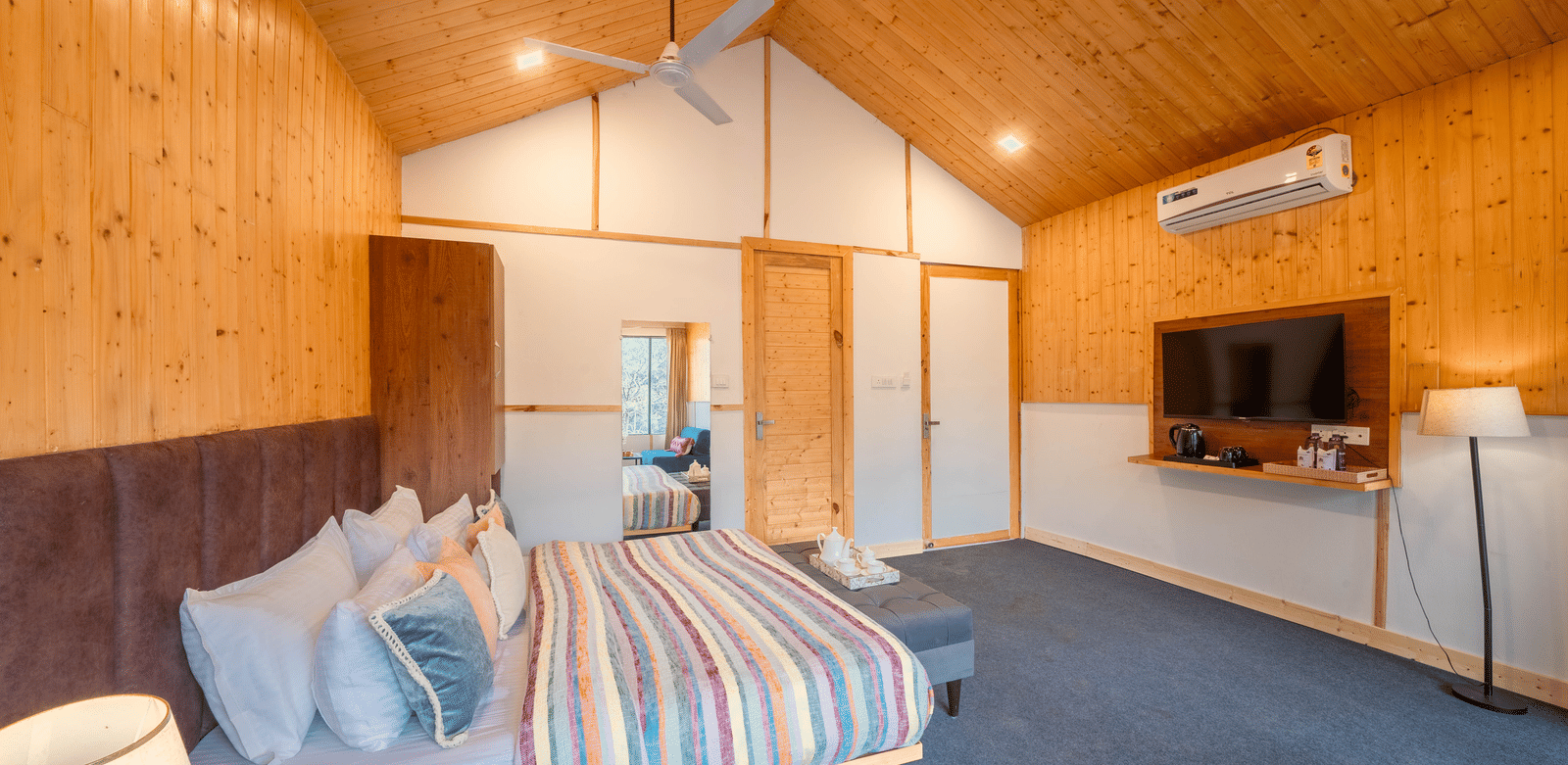 A room at Perfect Stayz The Jungle Resort contains a bed, a television mounted on a wall, and wooden paneling.
