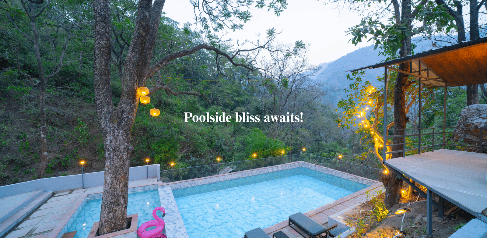 A swimming pool at Perfect Stayz The Jungle Resort is surrounded by trees and lounge chairs.