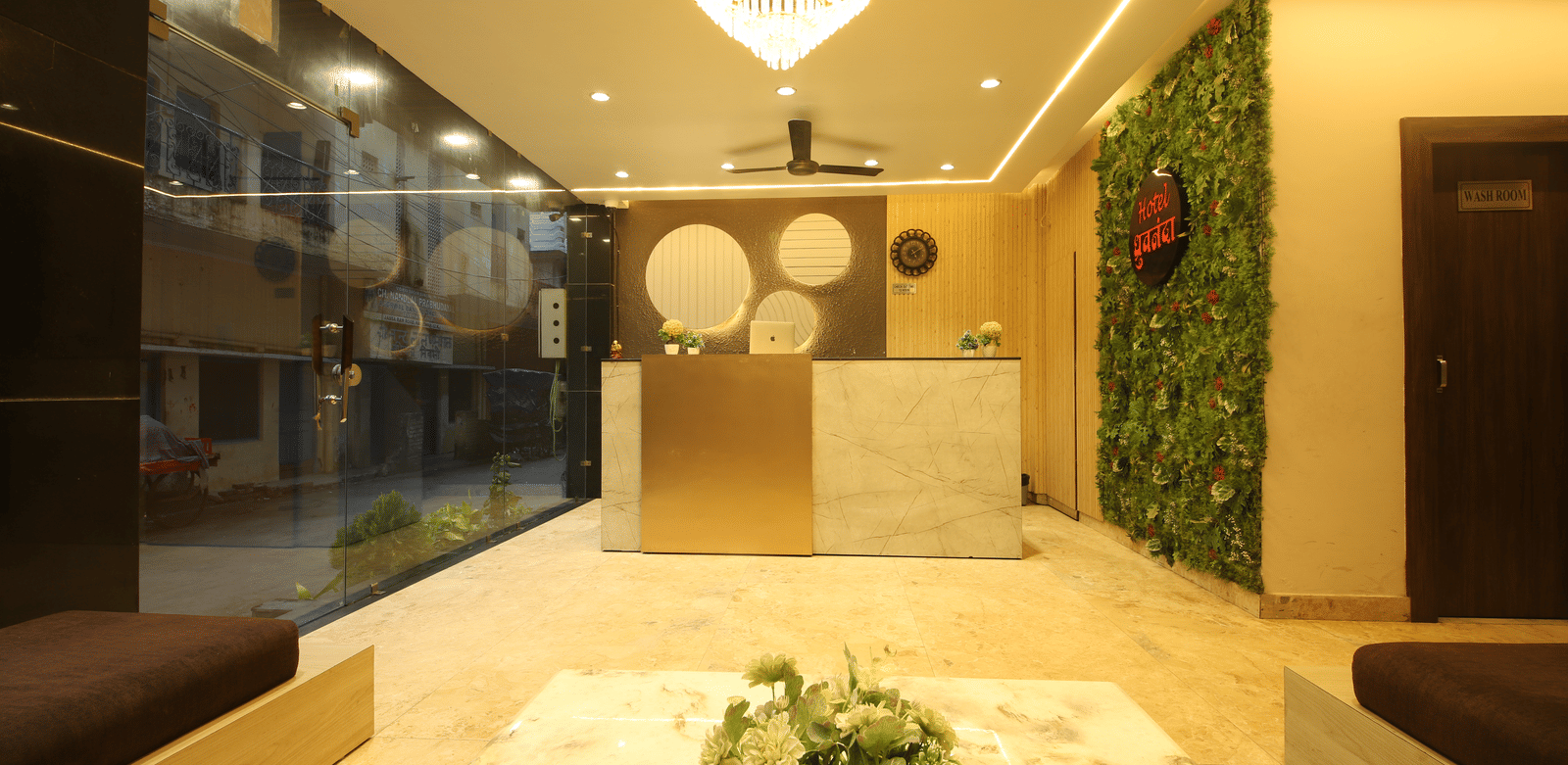 Front view of the reception desk with tall glass windows on one side of the desk at Perfectstayz Value Dhruv Nanda.