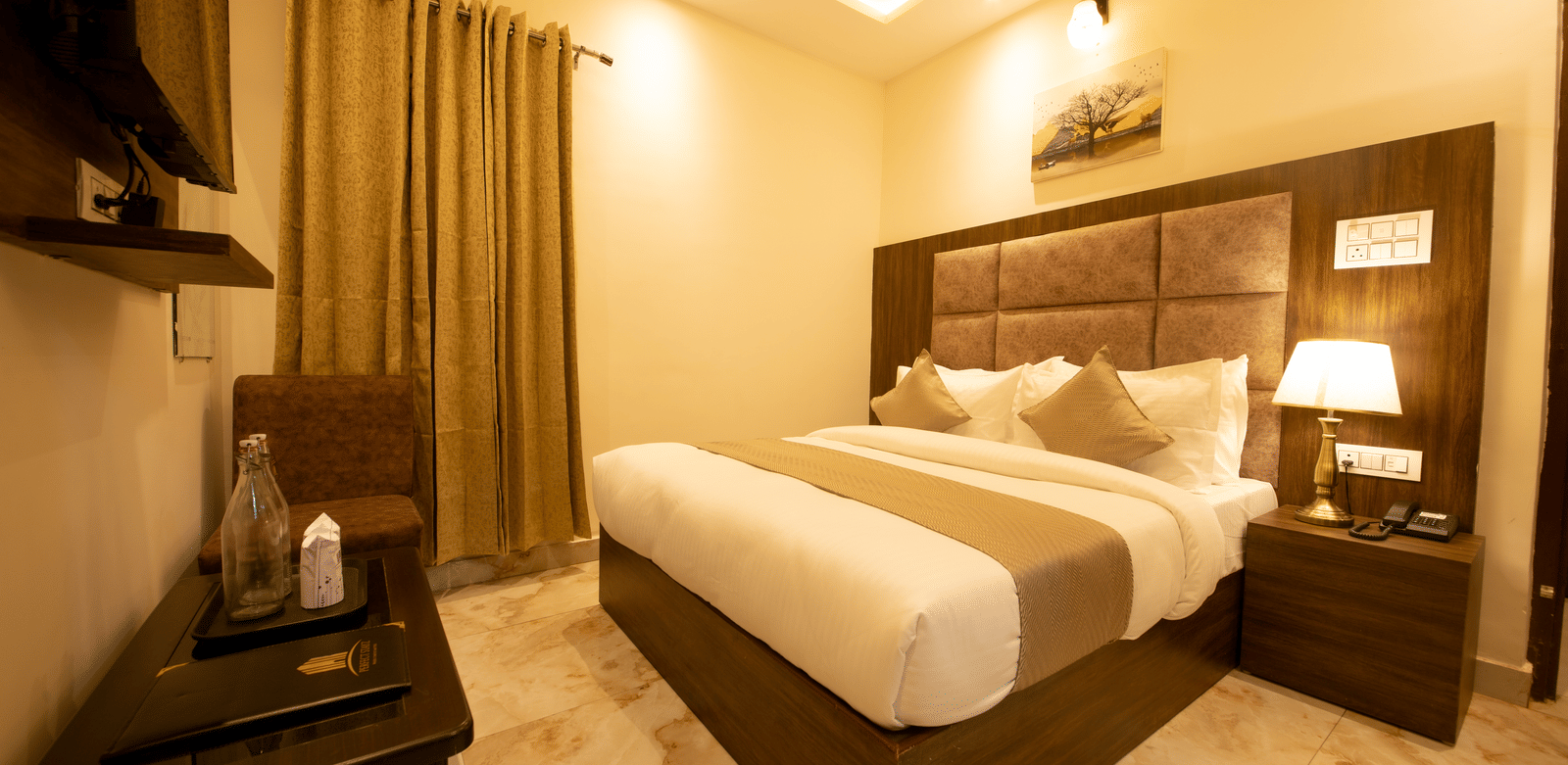 Corner view of the Deluxe Room with warm lighting featuring a wall-mounted television at the Perfectstayz Value Dhruv Nanda.