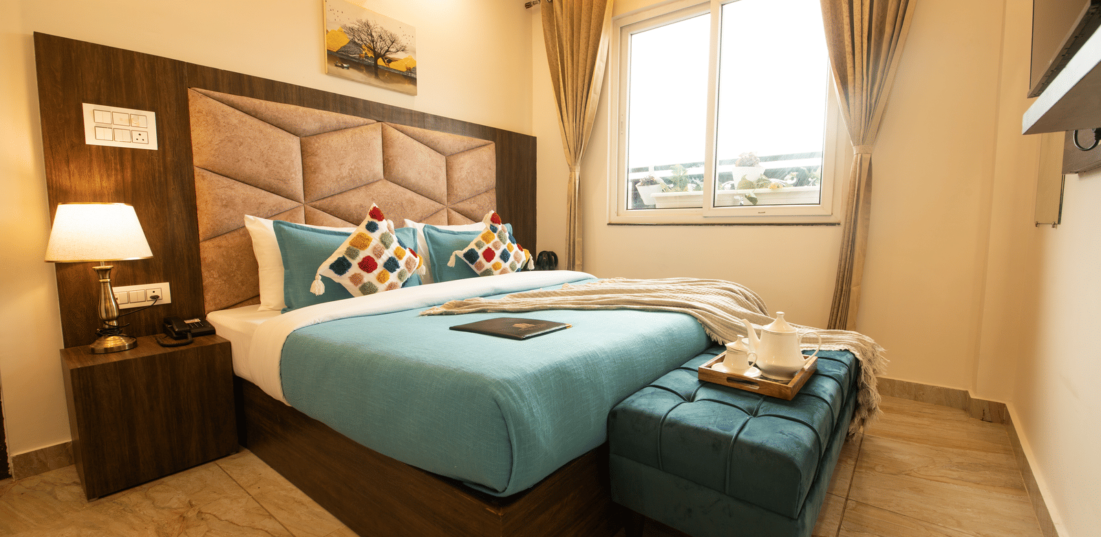 A corner-view shot taken from a lower angle of the double bed at the Executive Room with ample of natural light coming from the window beside it at the Perfectstayz Value Dhruv Nanda.