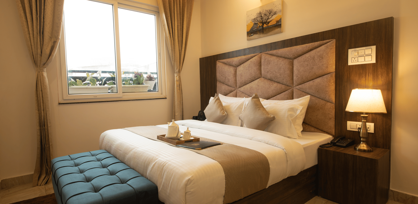 Side view of the double bed at the Executive Room featuring a brightly illuminated table lamp on the bed-side table at Perfectstayz Value Dhruv Nanda.