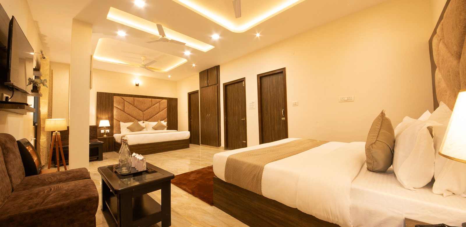 A wide-angle shot of the Family Room featuring a brightly-lit room with 2 double beds and a seating area in the corner.