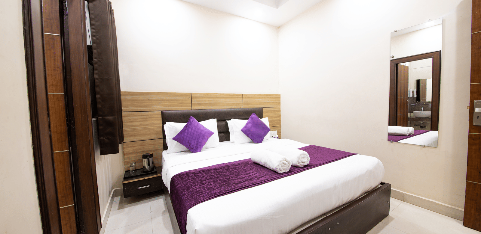Interior view of a hotel room showing a double bed and reflection in a mirror at Perfectstayz Value Dwarkesh, Haridwar.