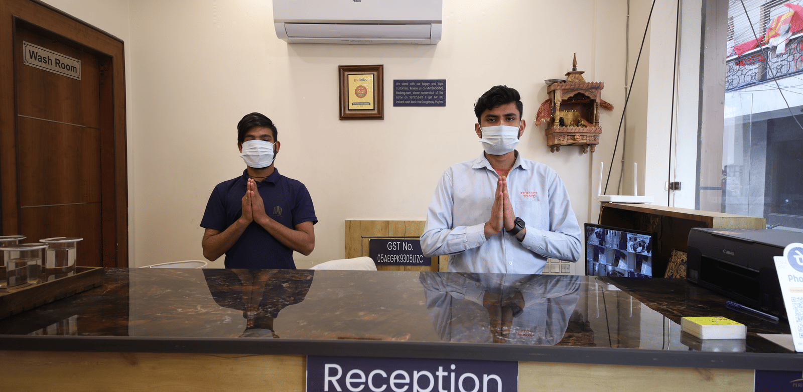 Interior view of staff wearing masks at the reception desk greeting guests at Perfectstayz Value Dwarkesh, Haridwar.