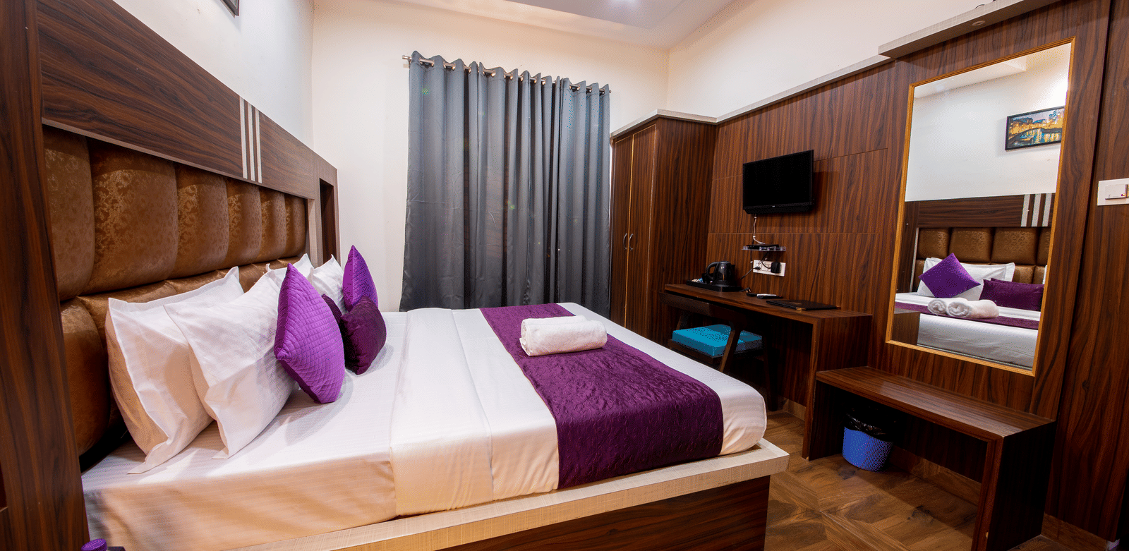 Bright hotel room with a large bed, wooden wardrobe, vanity mirror, and modern lighting fixtures - Perfectstayz Value Grey Castle, Haridwar