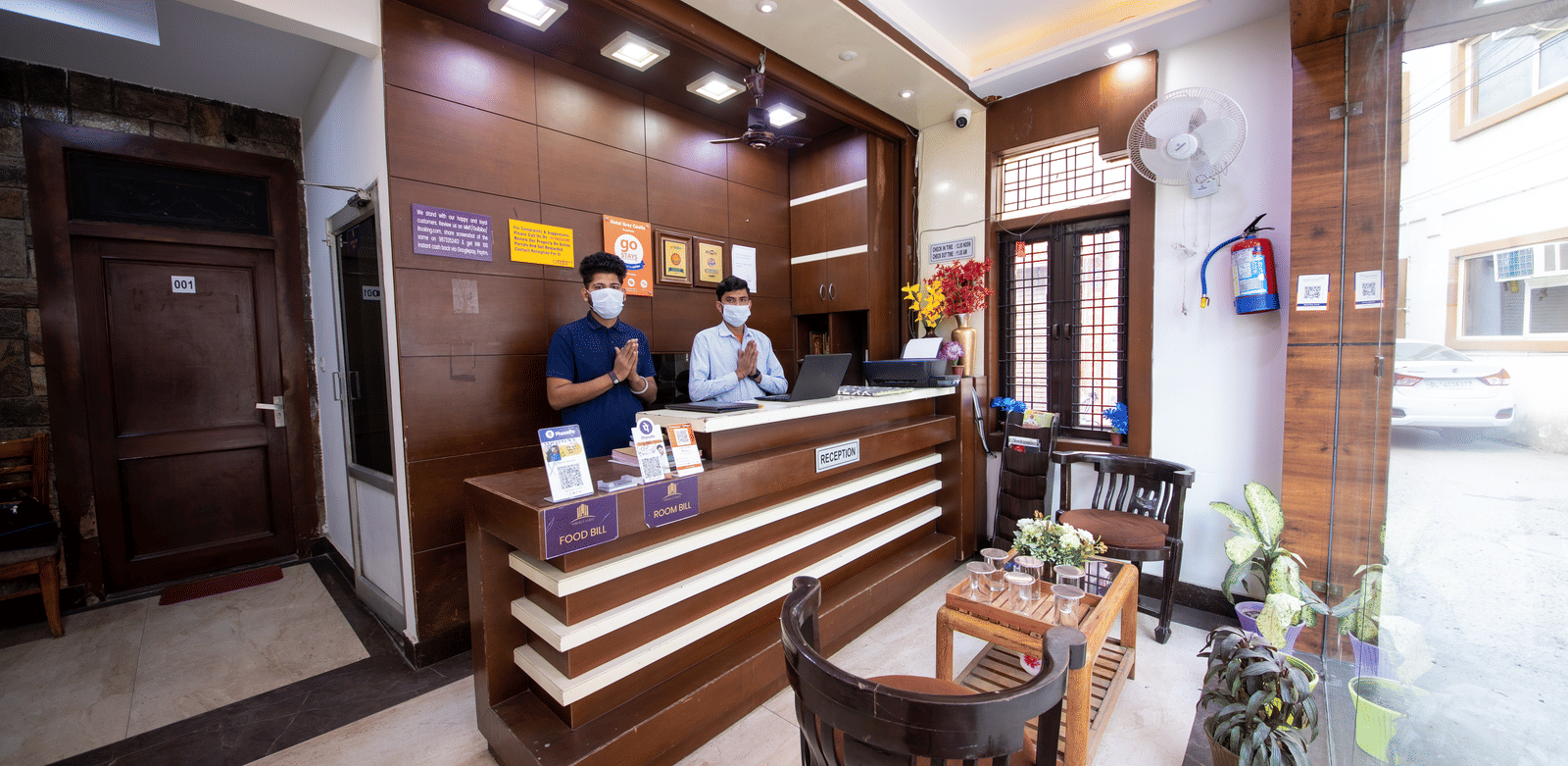 Hotel reception area featuring a modern wooden desk, staff behind the counter, and a small seating area - Perfectstayz Value Grey Castle, Haridwar