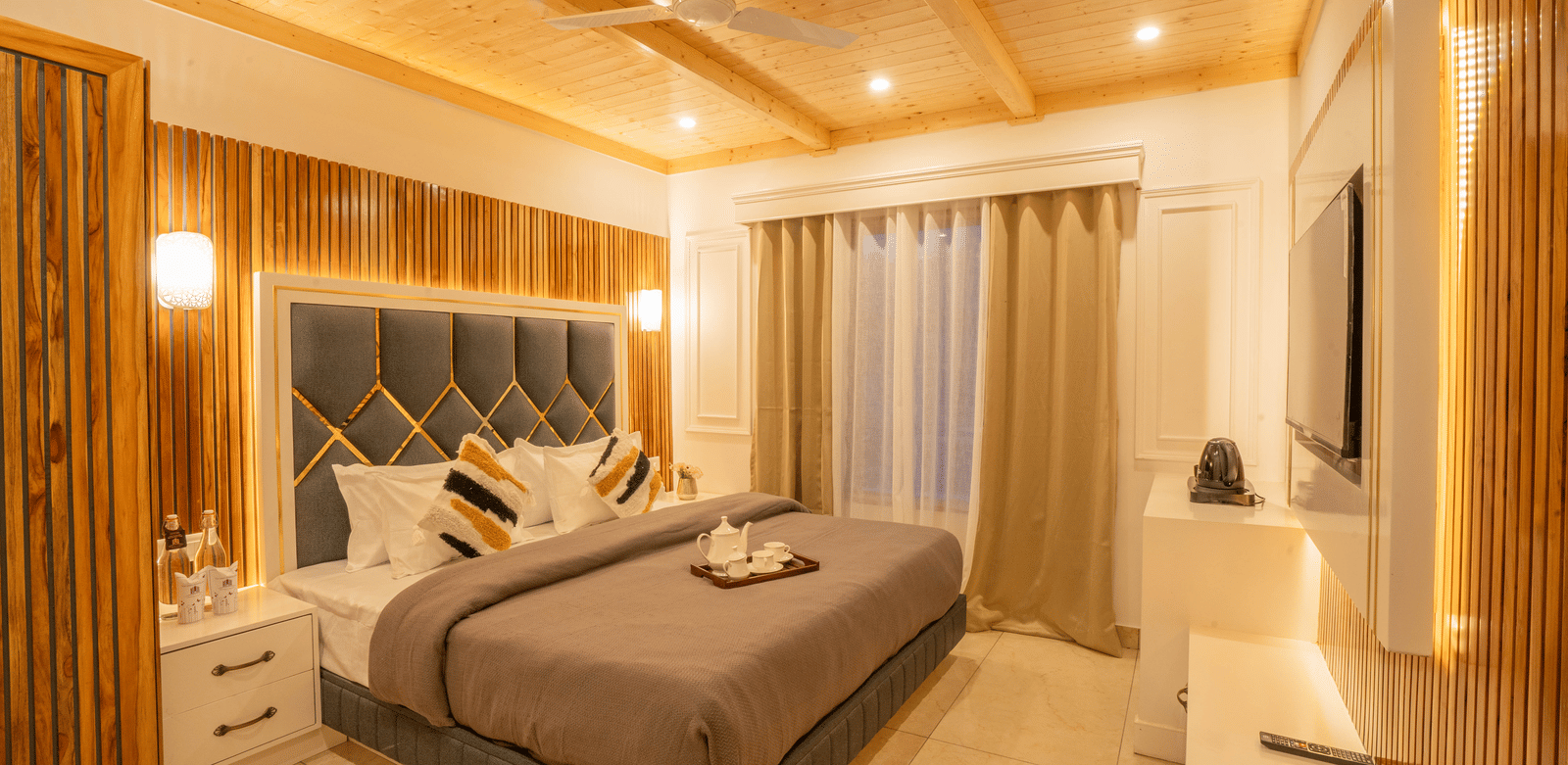 A bedroom with a king size bed, a bedside table, a flat-screen TV, and a media console at Perfectstayz Value Paradise, Mussoorie.