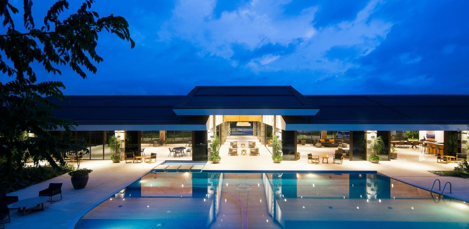 the exterior facade of a hotel with a swimming pool in front during blue hour
