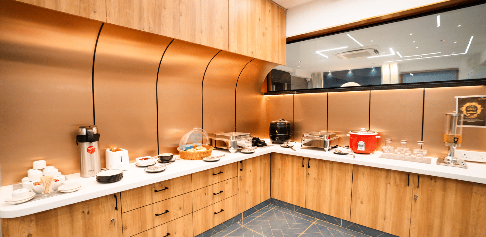 Dining area with buffet setup on an L-shaped counter featuring various dishes and cutlery at Sunrise Business Hotel, Hyderabad.