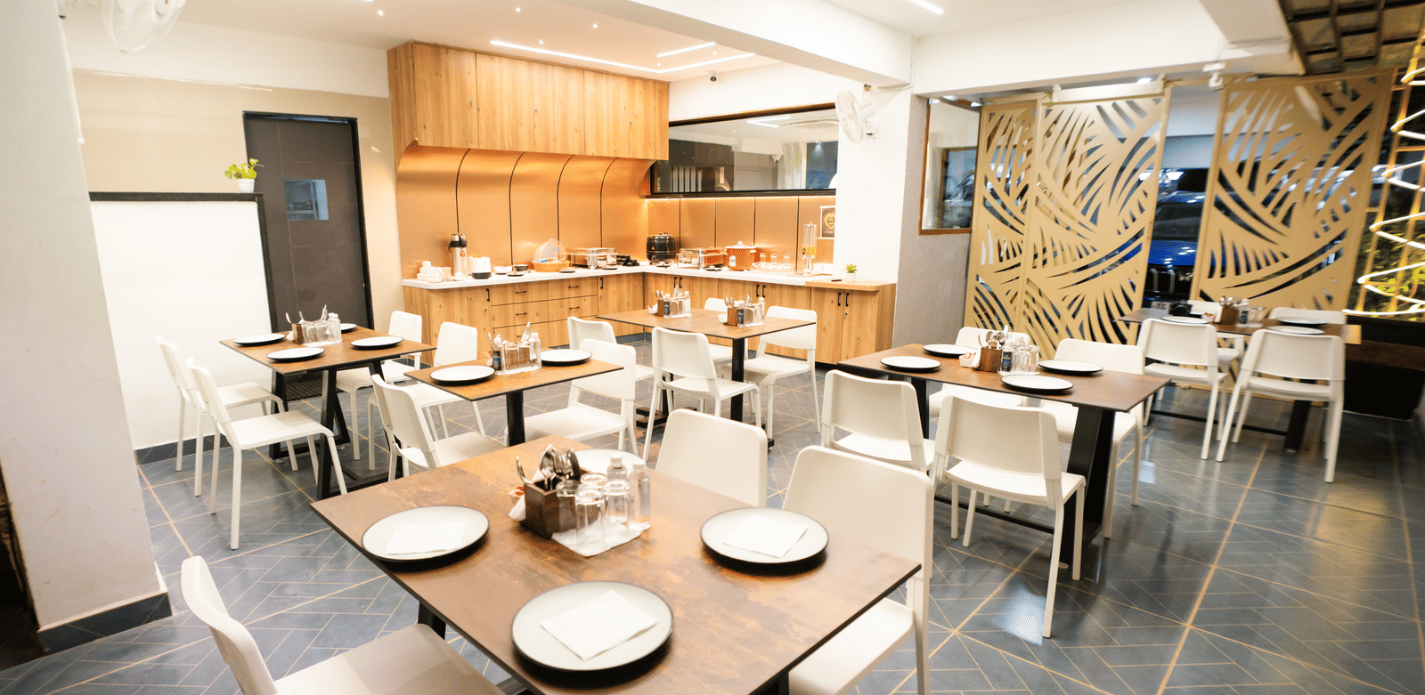 Restaurant seating area with tables and chairs set for dining at Sunrise Business Hotel, Hyderabad.