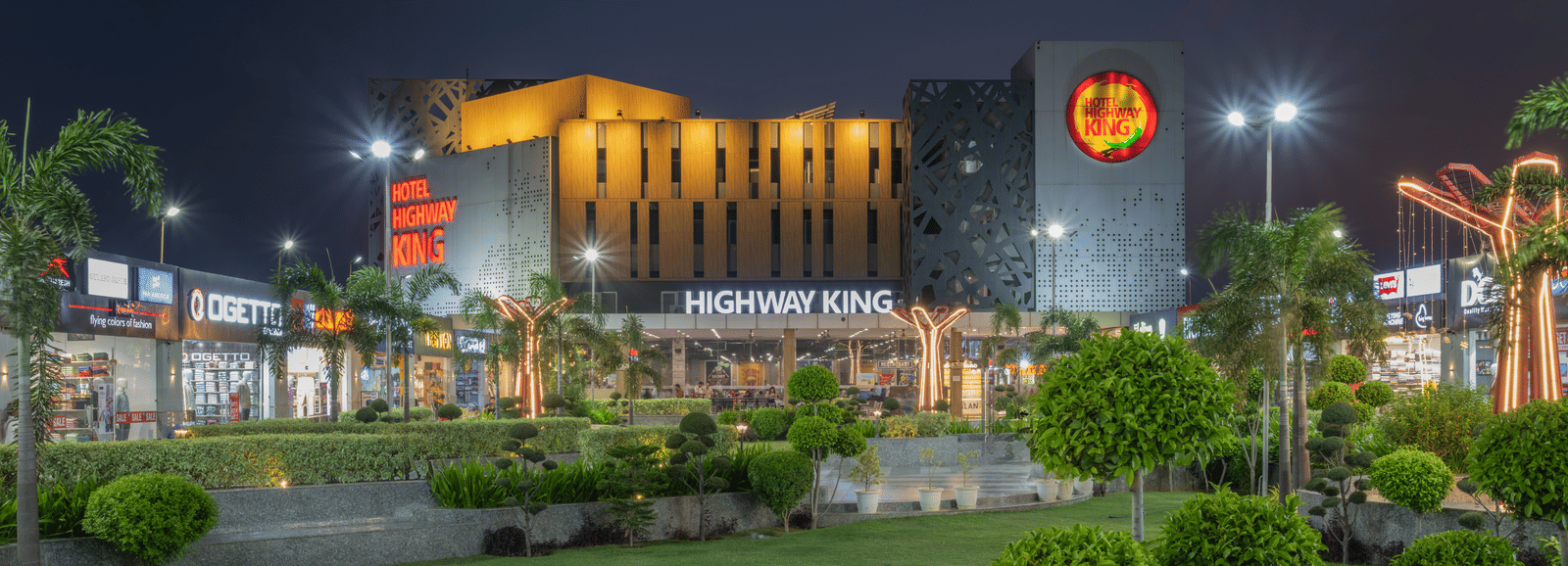 Night view of the well-lit exterior and gardens at Hotel Highway King, Bilaspur.