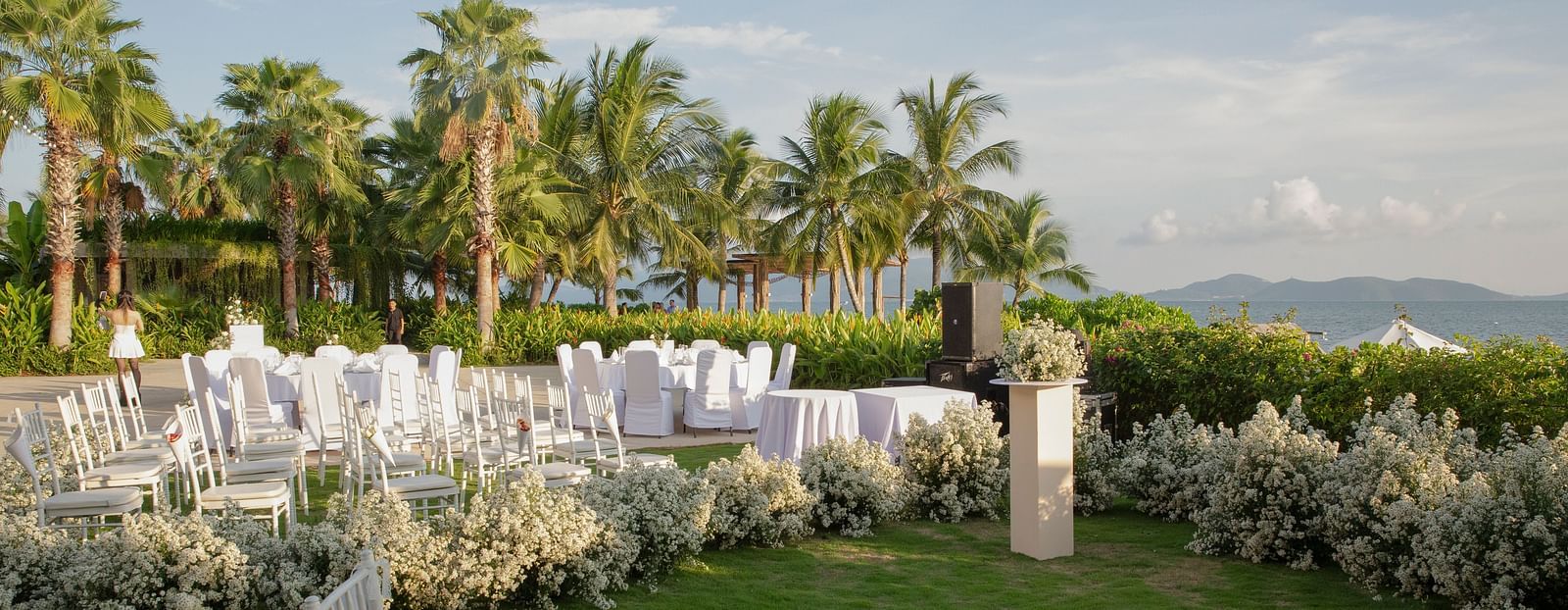 A lawn near the bay with white chairs - Alibu Resort Nha Trang