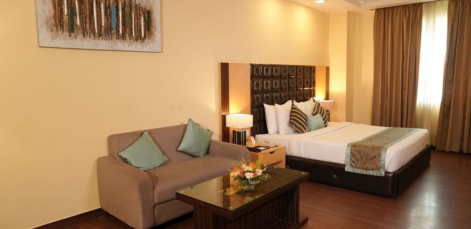 Spacious hotel room with a bed, seating area, and large window - Grand Plaza Lords Inn Jammu