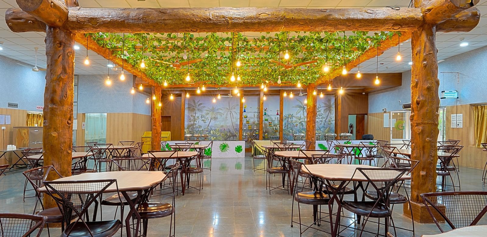 A well-lit restaurant with tables and chairs and light bulbs hanging from the ceiling at Greens Inn - Best Dining Experience in Hyderabad.