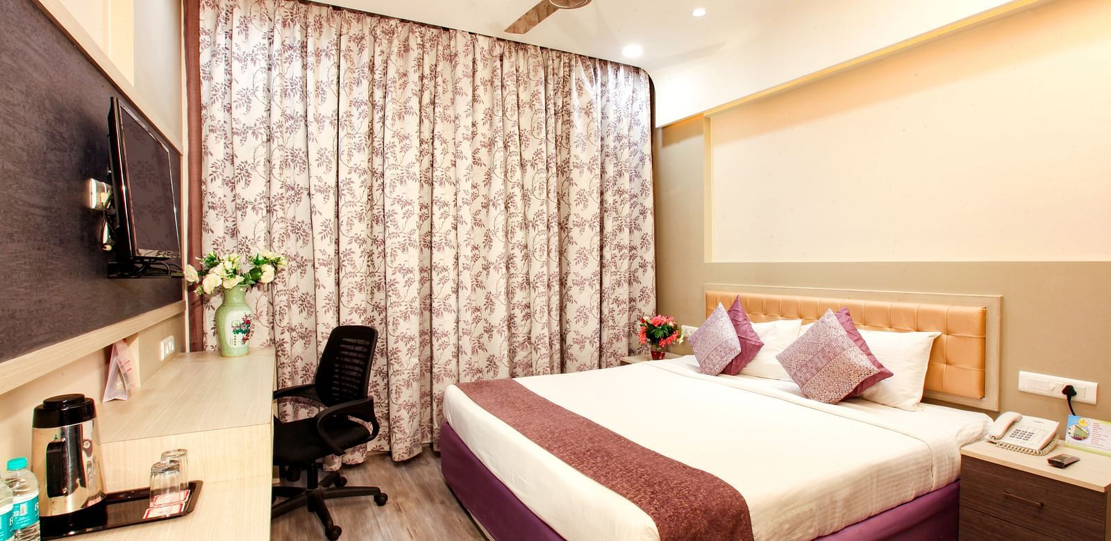 A well-appointed hotel room with a patterned headboard and modern amenities. - Tara, Comfort Hotel in Hyderabad - Ramoji Film City.
