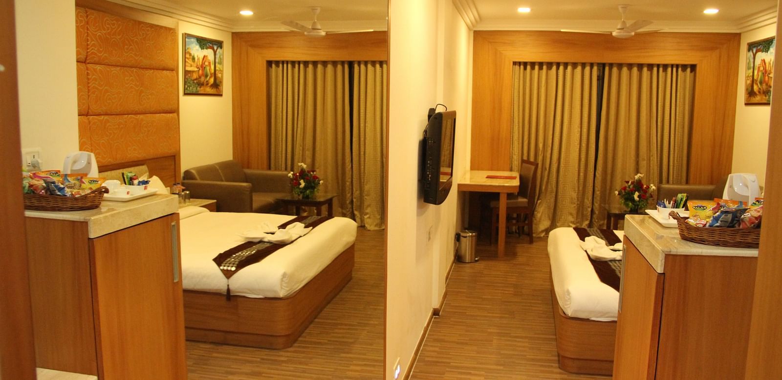 Spacious hotel room with sitting area and double bed, warmly lit