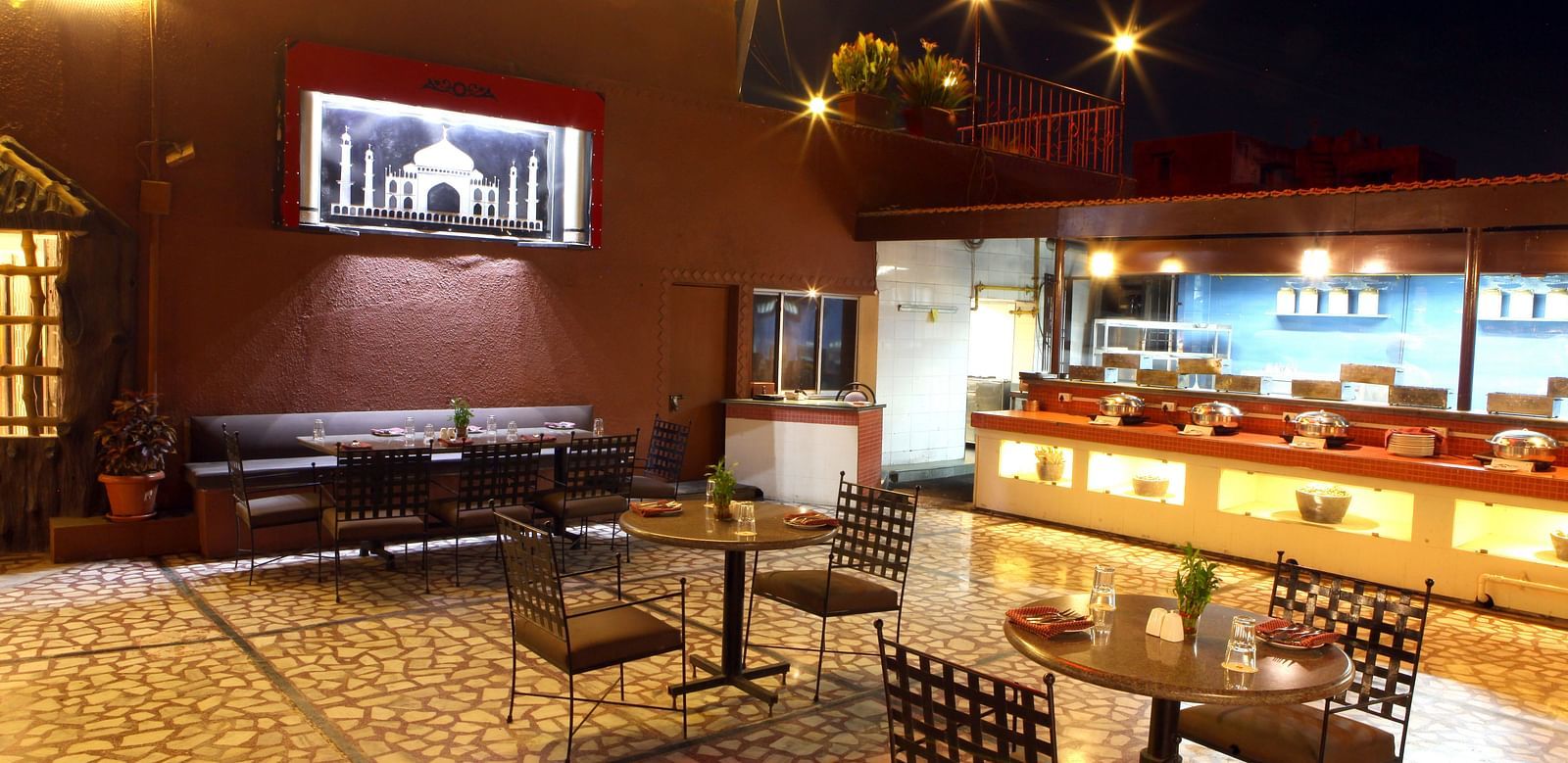 A warmly lit dining or lounge area with tables and chairs at Lords Plaza Surat.