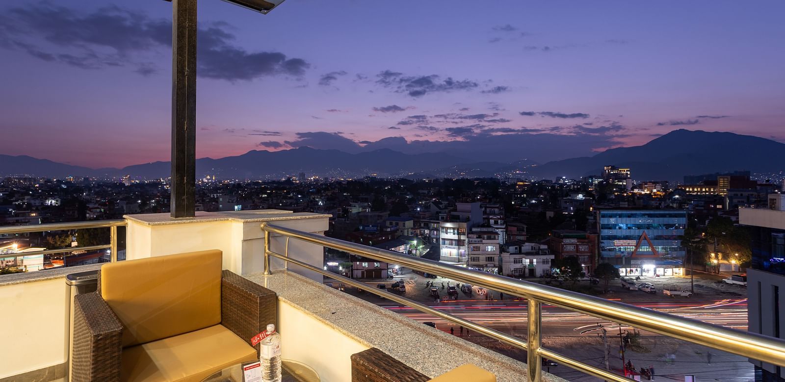 View of the purple and pink sky, urban and hilly landscape from an outdoors table at Mandala by Lords located in Mandala Norling Lords Prime, Kathmandu.