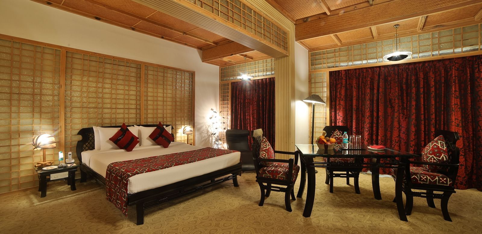 A sophisticated hotel room combining traditional design with modern amenities, featuring a large bed and seating area A grand hotel suite with an opulent red and white decor, large bed, and seating area, reflecting a traditional style at Sitara Luxury Hote