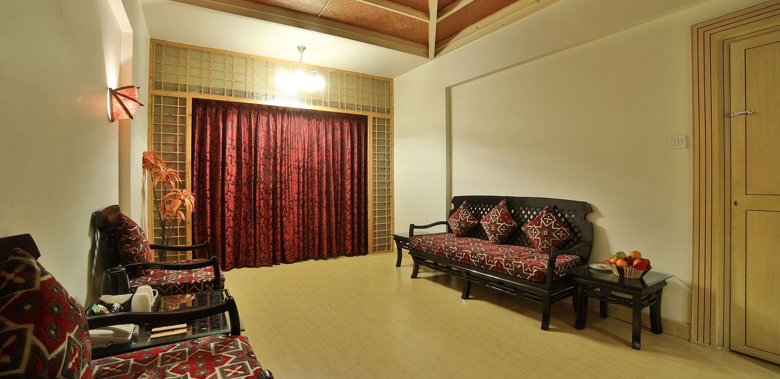 A spacious living area in a hotel suite with plush sofas, patterned upholstery, and a serene ambiance A grand hotel suite with an opulent red and white decor, large bed, and seating area, reflecting a traditional style at Sitara Luxury Hotel in Hyderabad n