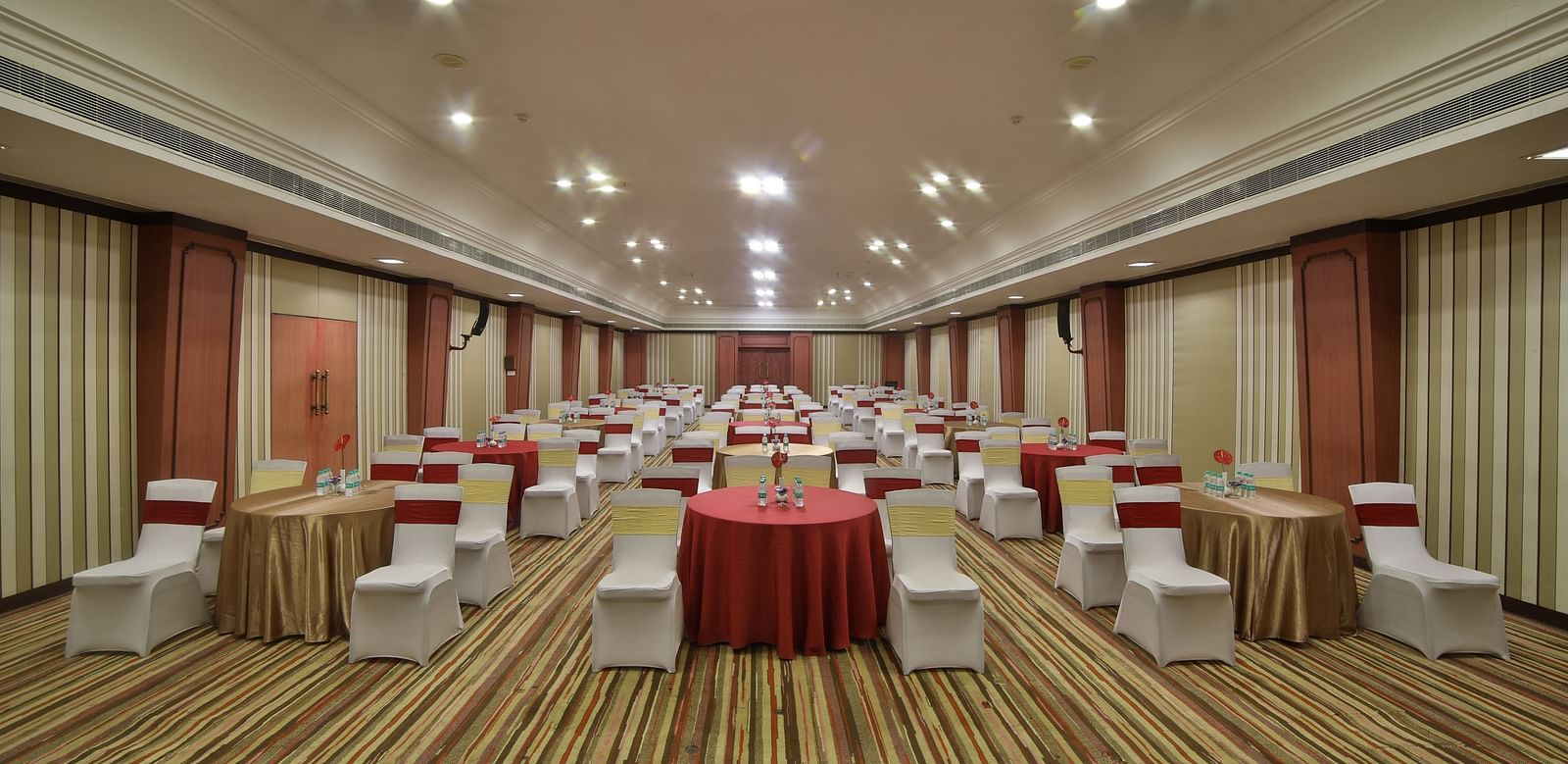  Seating arrangement in Terrace Hall A grand hotel suite with an opulent red and white decor, large bed, and seating area, reflecting a traditional style at Sitara Luxury Hotel in Hyderabad near Ramoji Film City.