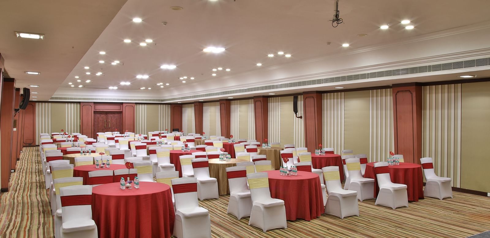  Seating arrangement in Terrace Hall A grand hotel suite with an opulent red and white decor, large bed, and seating area, reflecting a traditional style at Sitara Luxury Hotel in Hyderabad near Ramoji Film City.