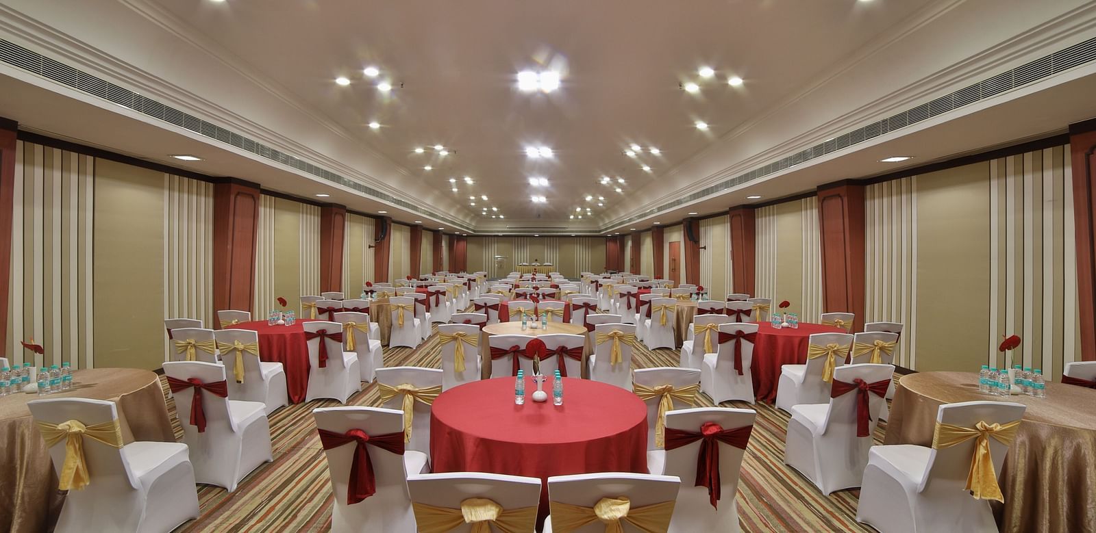  Seating arrangement in Terrace Hall A grand hotel suite with an opulent red and white decor, large bed, and seating area, reflecting a traditional style at Sitara Luxury Hotel in Hyderabad near Ramoji Film City.